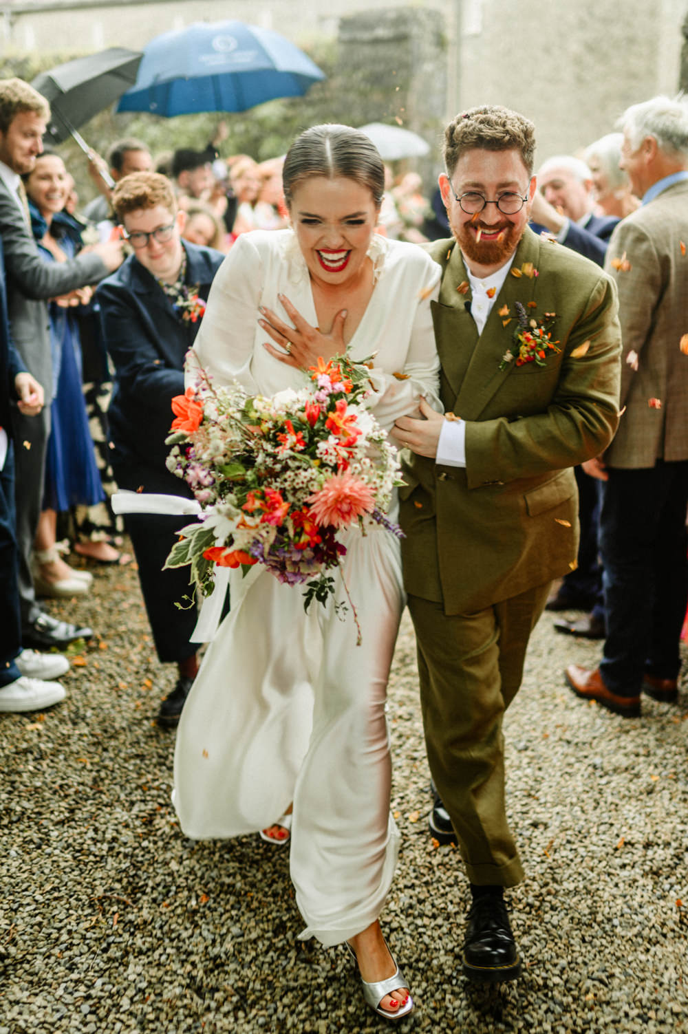 couples walking when crowd throwing confetti at them on the way out after ceremony in juniper barn